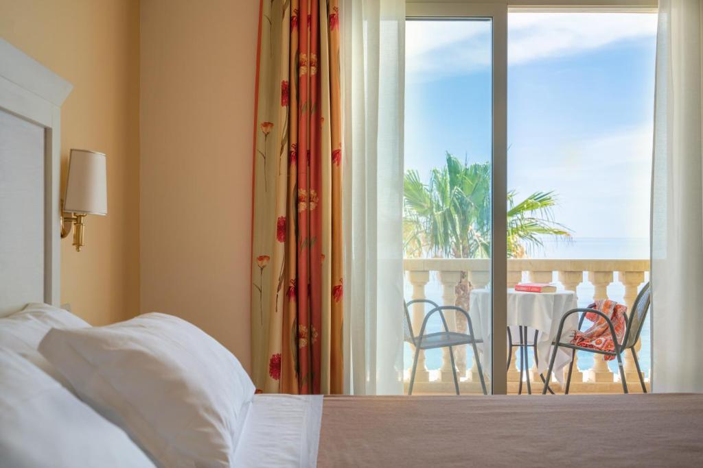 a bedroom with a bed and a balcony with a table and chairs at Hotel Orizzonte in Letojanni