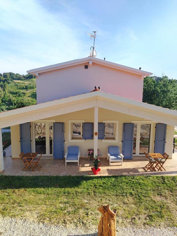 ein rosafarbenes Haus mit Stühlen und Tischen auf einer Terrasse in der Unterkunft B&bo in Pesaro