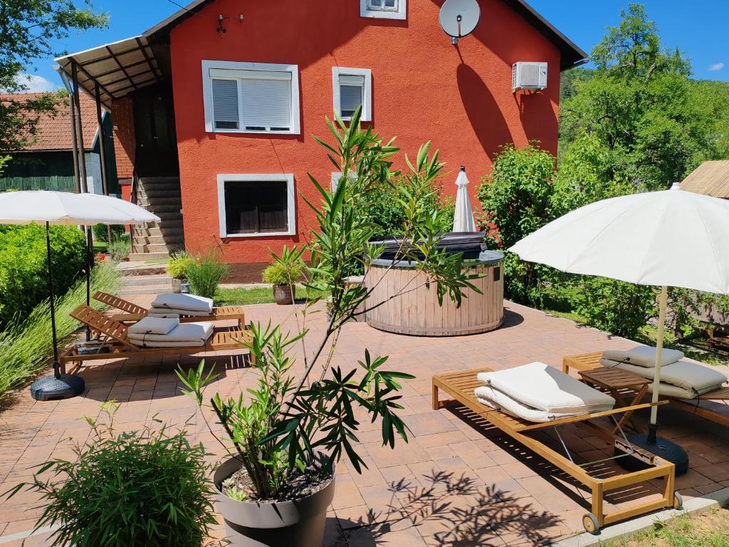 a patio with chairs and umbrellas in front of a house at Holiday Home Modric in Otočac