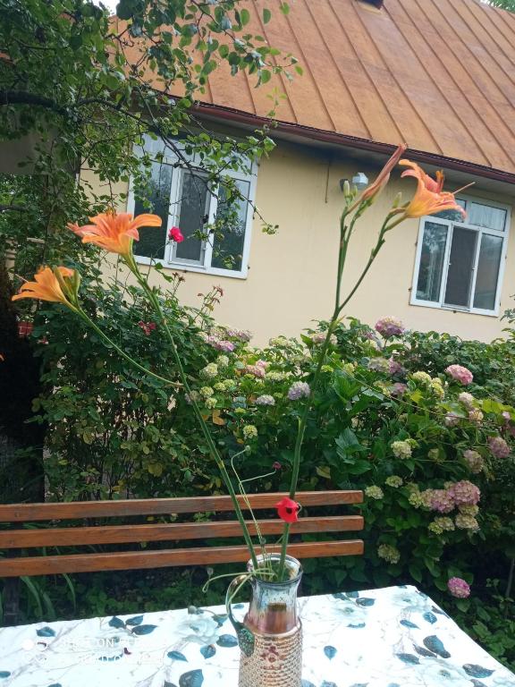 a vase with flowers on a table with a bench at Фазенда in Gabala