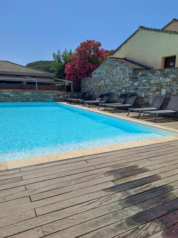 a swimming pool with chairs next to a stone wall at Studio sisco in Sisco