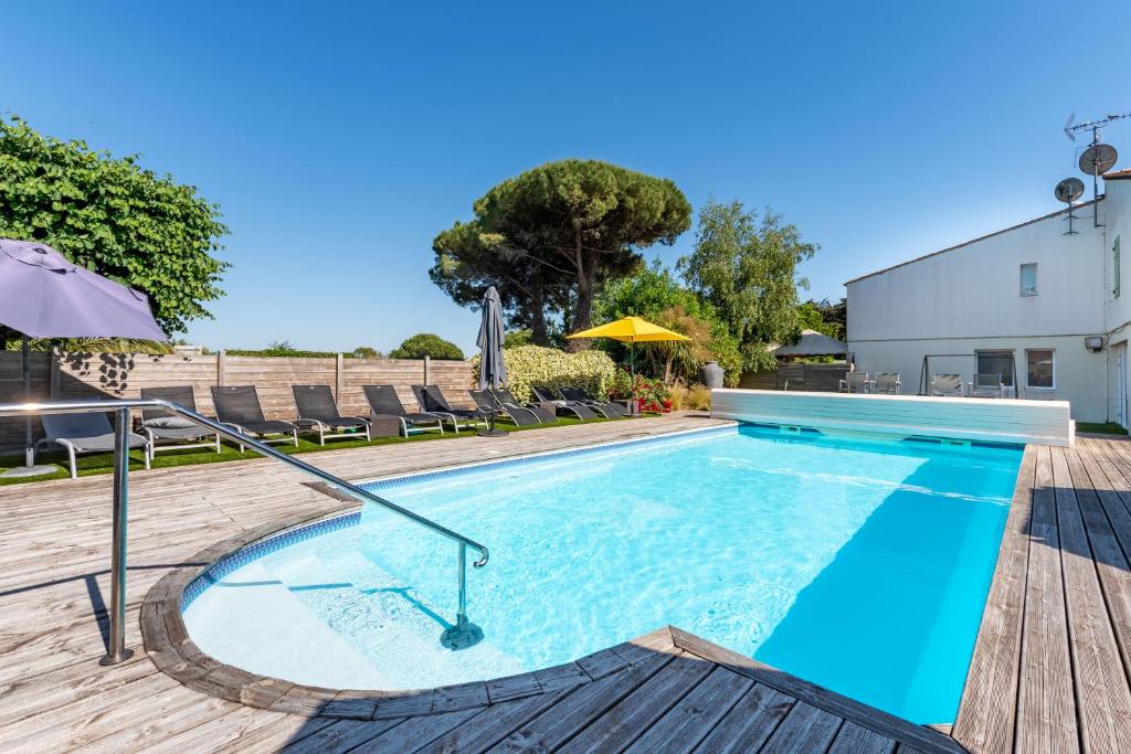 a swimming pool with chairs and an umbrella at Hôtel Le Parasol in Ars-en-Ré