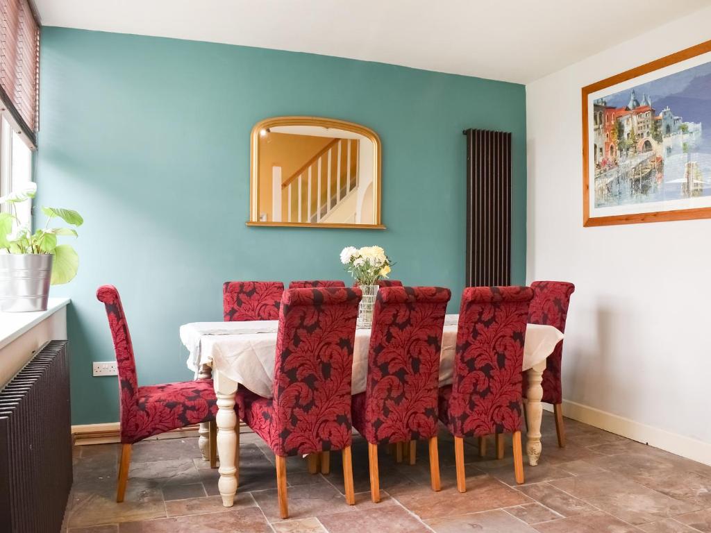 a dining room with a table and red chairs at Rose Croft in Pickering