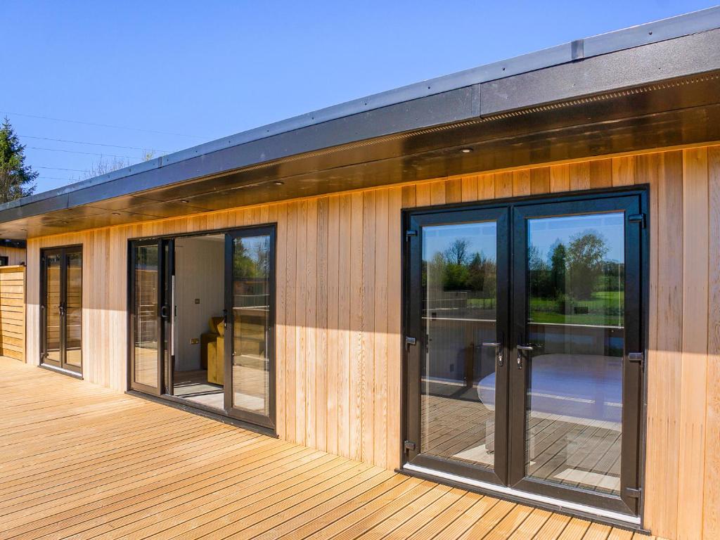 a building with glass doors on a wooden deck at Hummingbird Lodge - Uk51940 in Yarm