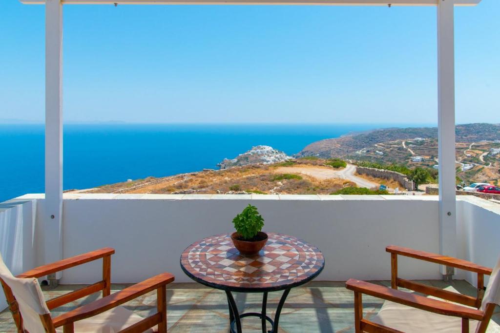 a table and chairs on a balcony with a view of the ocean at Studios Poulati in Artemonas