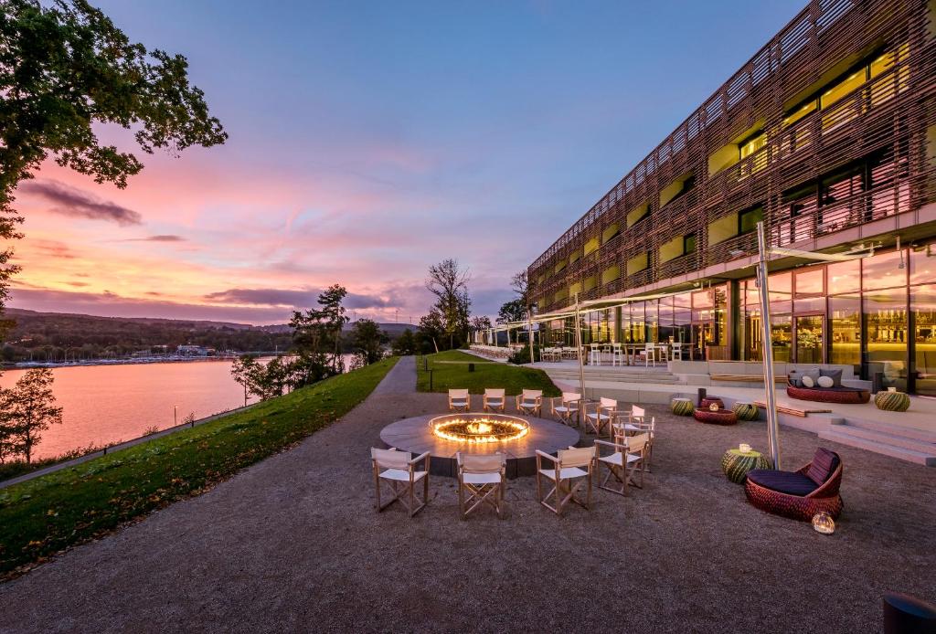 a building with a table and chairs next to a lake at Seezeitlodge Hotel & Spa in Gonnesweiler