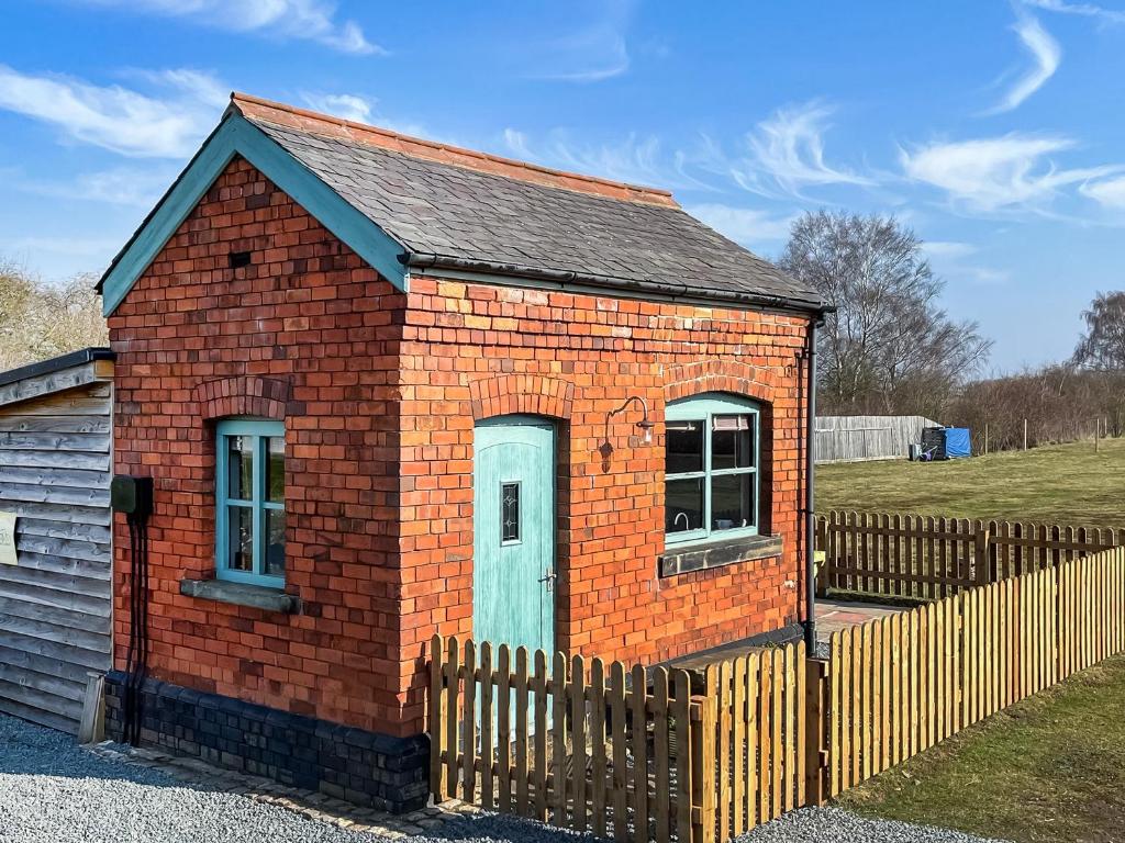 a small brick house with a wooden fence at The Weighbridge in North Clifton