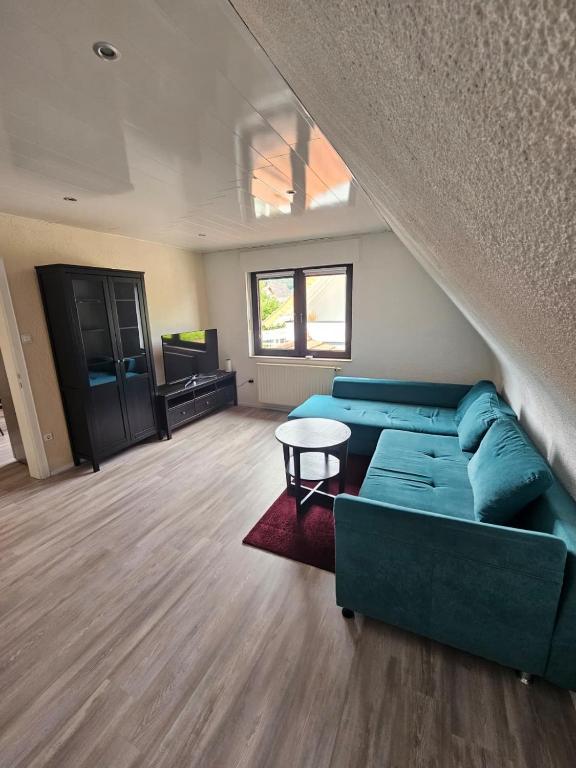a living room with a blue couch and a table at FeWo Zimmer Waldmohr in Waldmohr