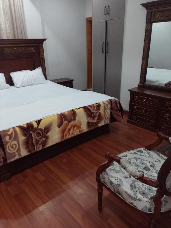 a bedroom with a bed and a chair and a mirror at Daisy Cottage in Murree