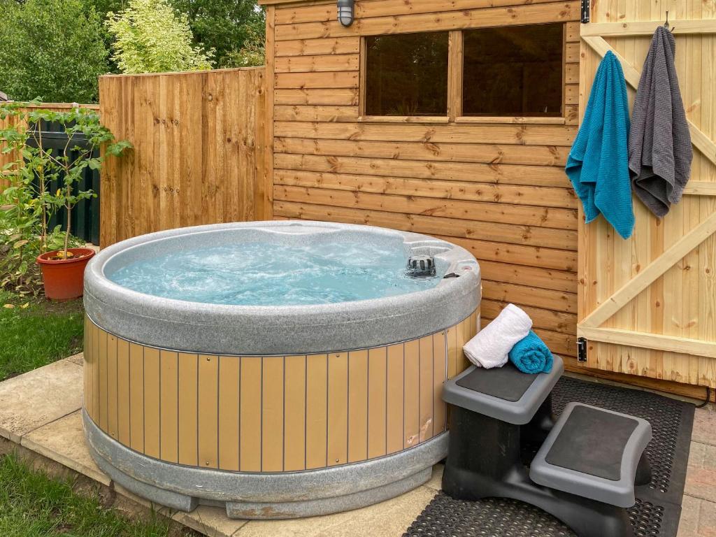 a hot tub in a backyard next to a wooden building at Dippers in Smallburgh