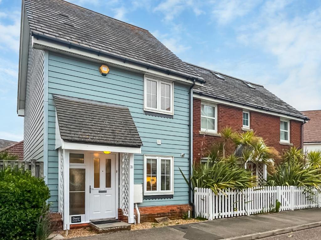 a blue house with a white fence at Dory in Rye