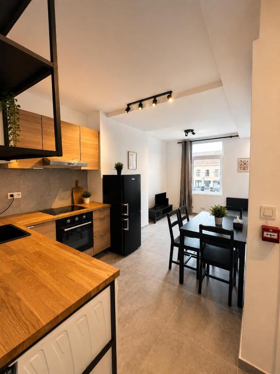 a kitchen and dining room with a black refrigerator and a table at Les lodges d'Eva de Chièvres in Chièvres