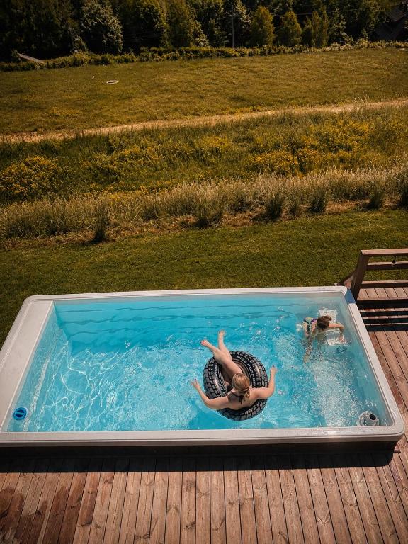 a person laying in a swimming pool on a deck at Siedlisko nad Cisowcem Bieszczady in Cisowiec