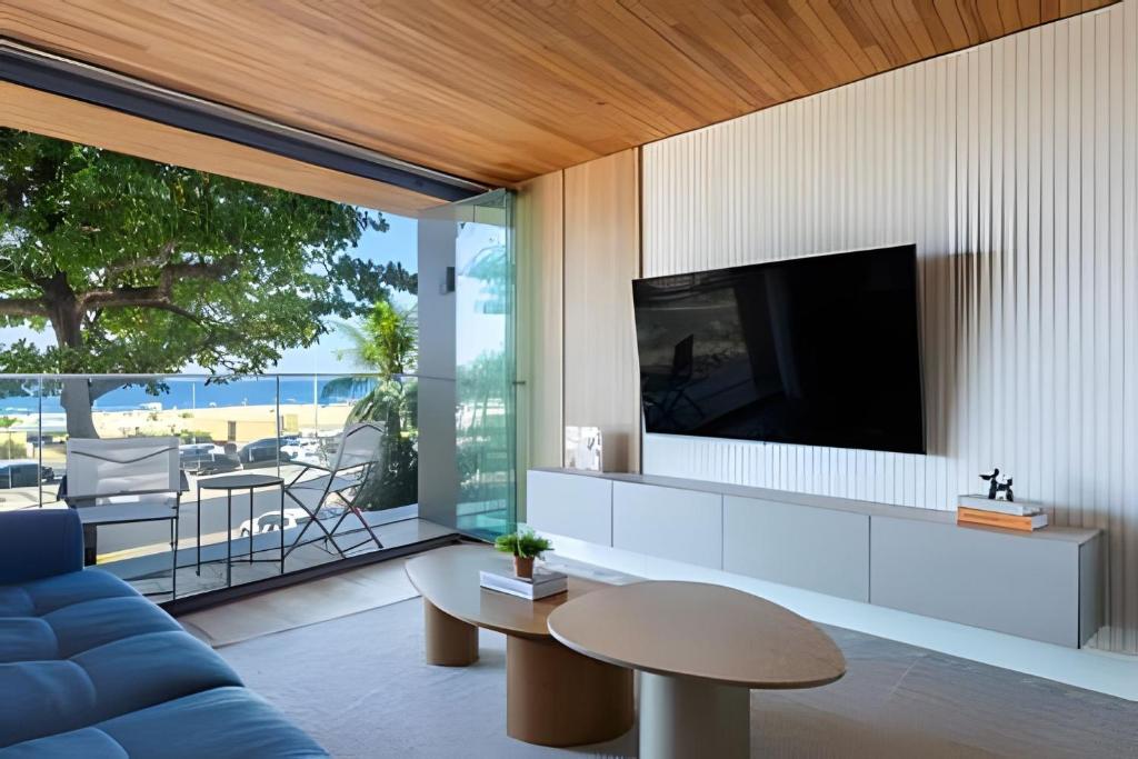 a living room with a blue couch and a tv at Azure Loft: Sea & Luxury in Rio de Janeiro