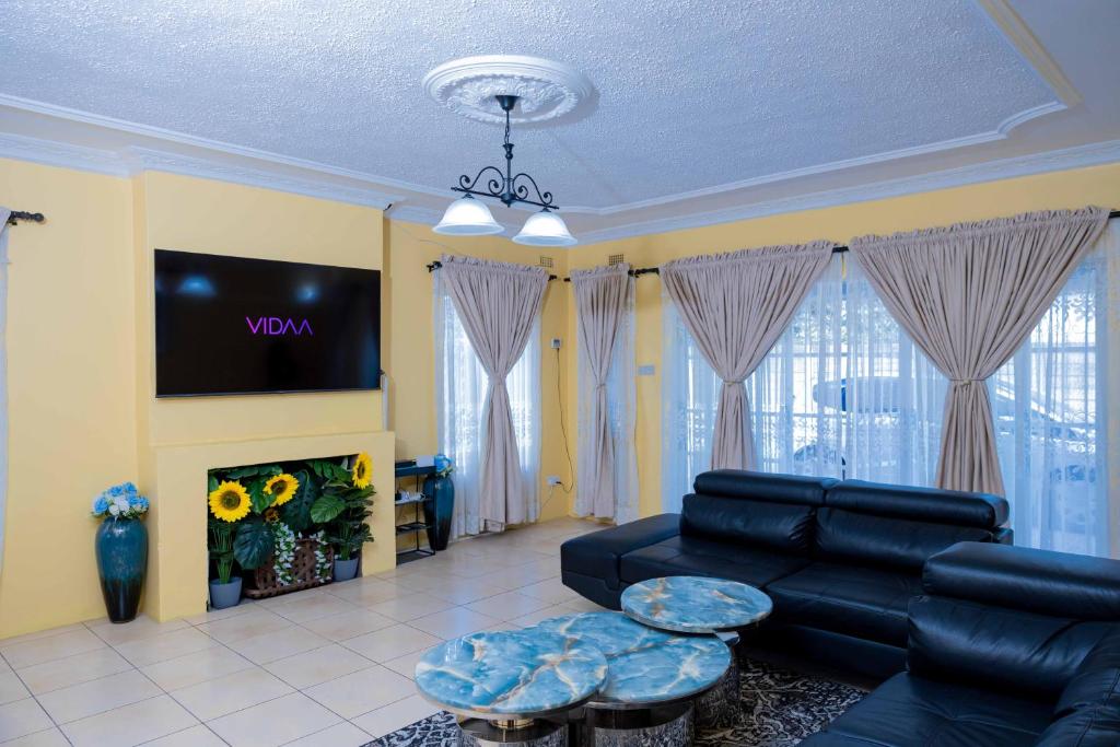 a living room with a black couch and a tv at Mainway home in Harare