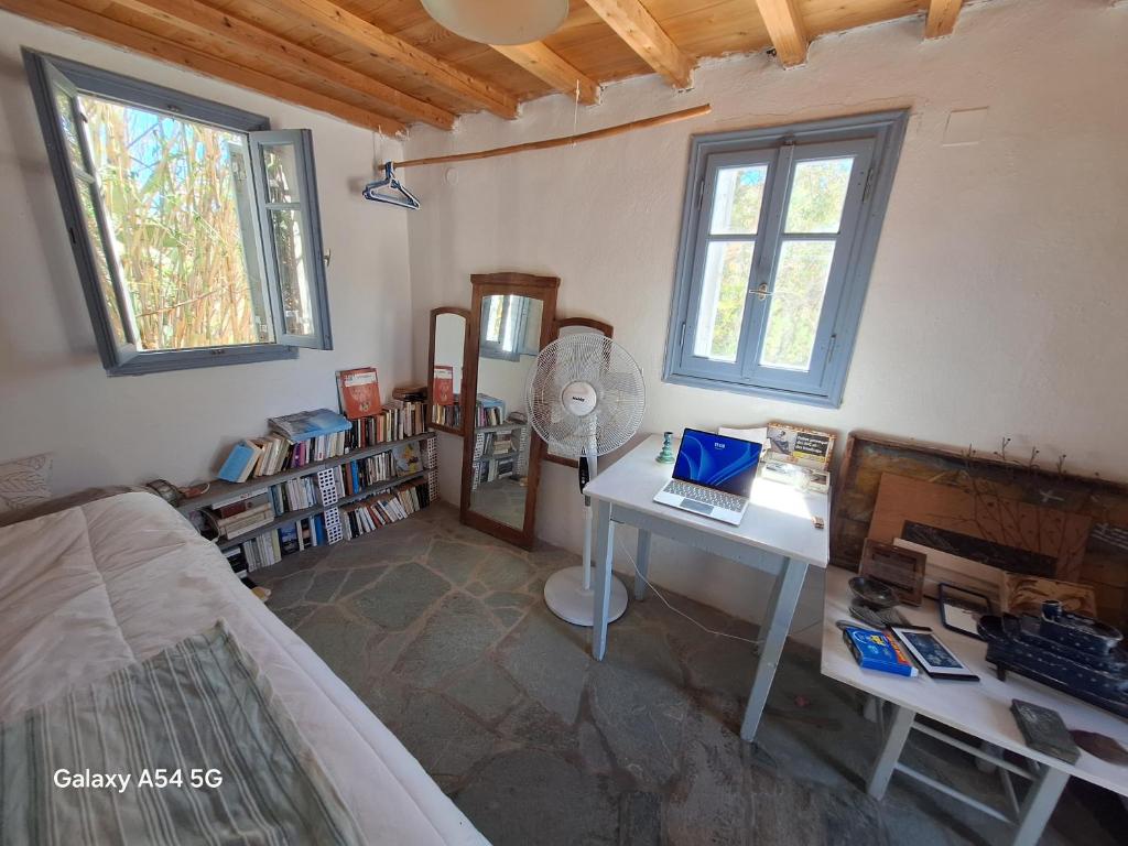 a room with a bed and a desk with a laptop at Charmante maison cycladique traditionnelle in Faros
