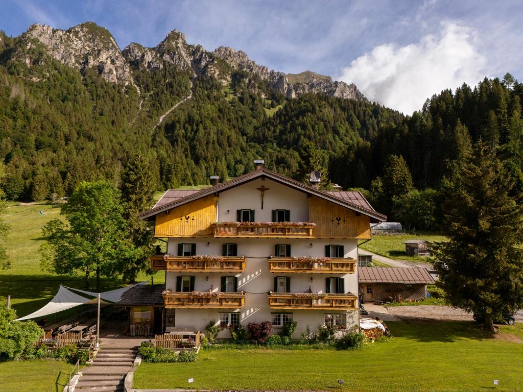 a building in a field with mountains in the background at Rifugio Cereda in Fiera di Primiero