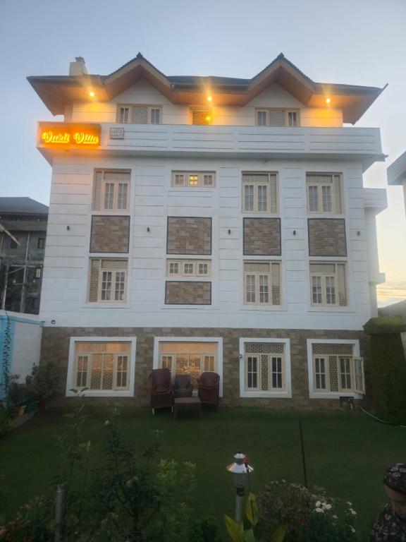 a large white building with chairs in front of it at Vakil Villa in Srinagar