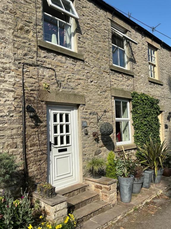 a stone house with a white door and stairs at Middle Cottage in Middleham