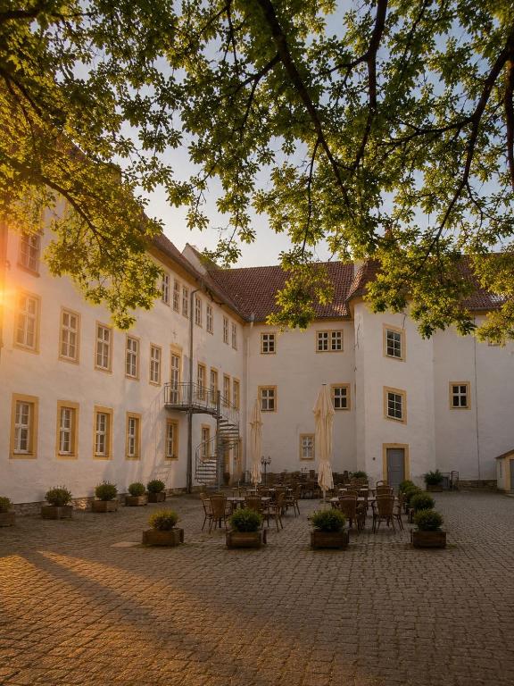 a large white building with tables and chairs at Schlosshotel am Hainich in Hörselberg-Hainich