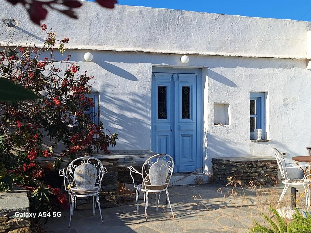 a white building with a blue door and chairs at Ancienne ferme traditionnelle in Katavatí