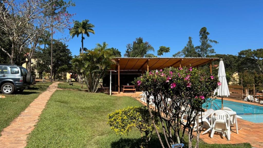 a backyard with a pool and a table and a umbrella at Pousada Alto do Bau in Conceição do Mato Dentro