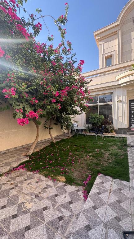a tree with pink flowers in front of a house at سفانه in Unayzah
