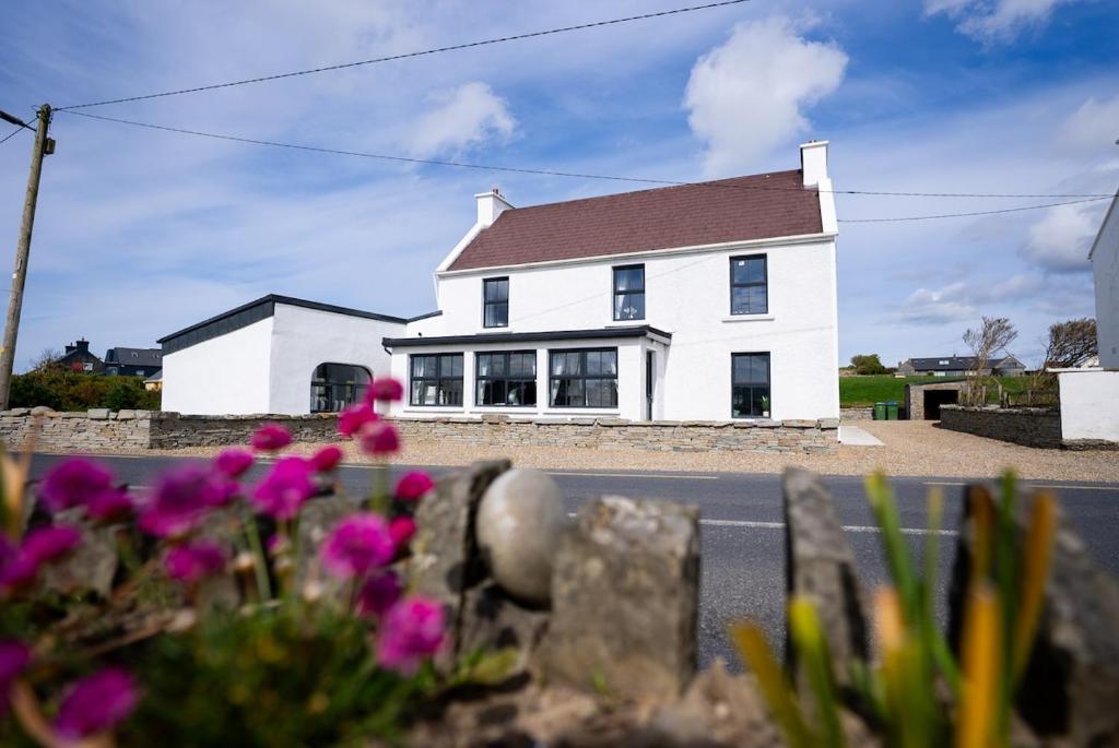 a white house with purple flowers in front of it at Harbour View - Sleeps 26 guests in Liscannor