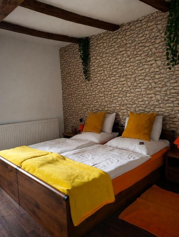 a bedroom with a bed with a yellow blanket on it at BODZA Apartment in Tompa