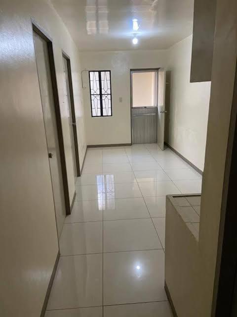 an empty room with white tile floors and a window at Bautista Apartments in Imus