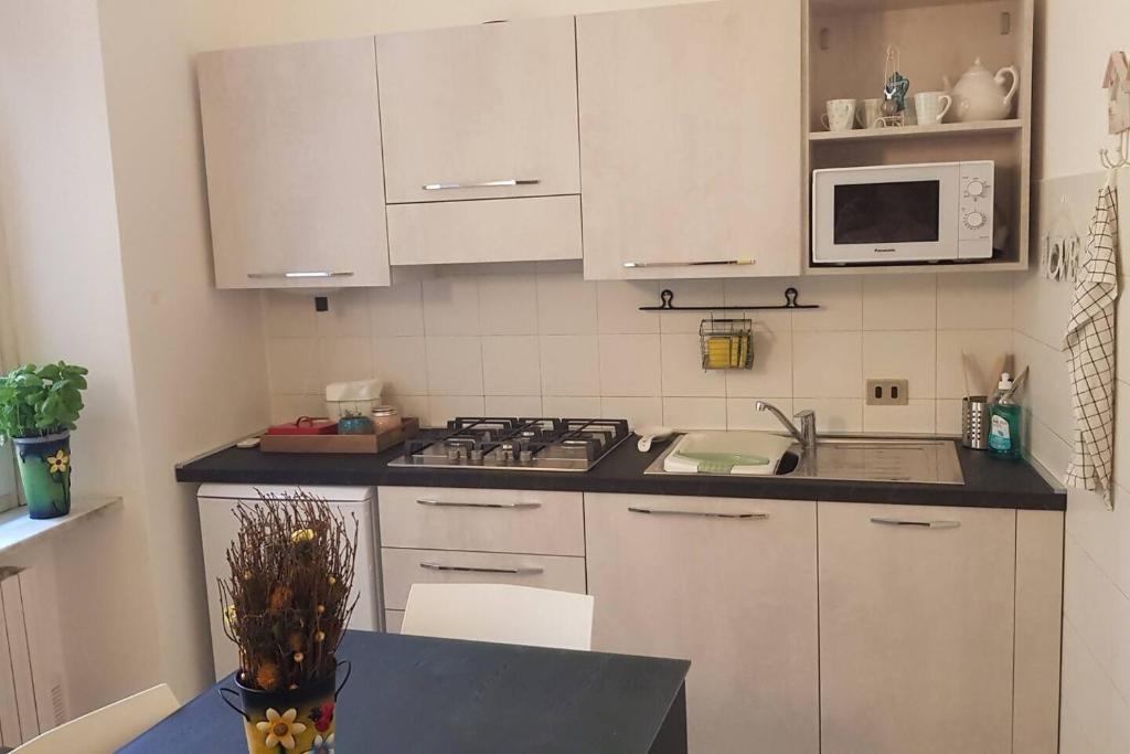a kitchen with white cabinets and a stove and microwave at Casa della Ludo Biella in Biella