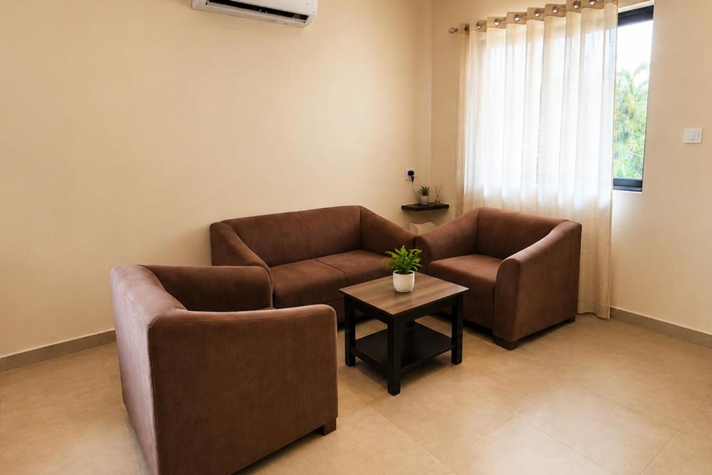 a living room with two couches and a table at Shiva Apartments & Stud!os GOA in Parra