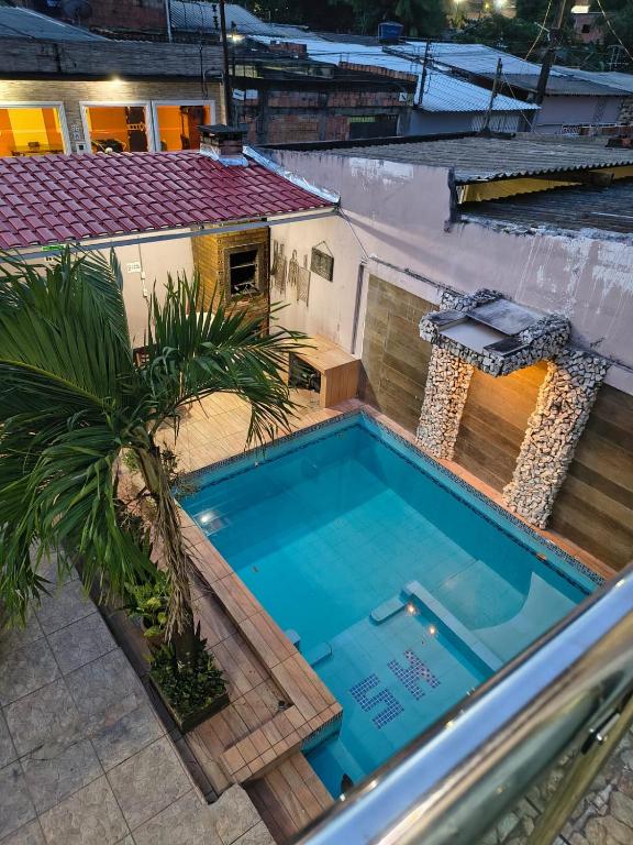 a swimming pool with a palm tree next to a house at Casa Privativa com Piscina, Churrasqueira, Wi-Fi e Ar-Condicionado em Manaus in Manaus