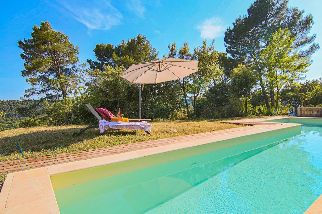 a table and an umbrella next to a swimming pool at House Pool Out In The Wilds in Salernes