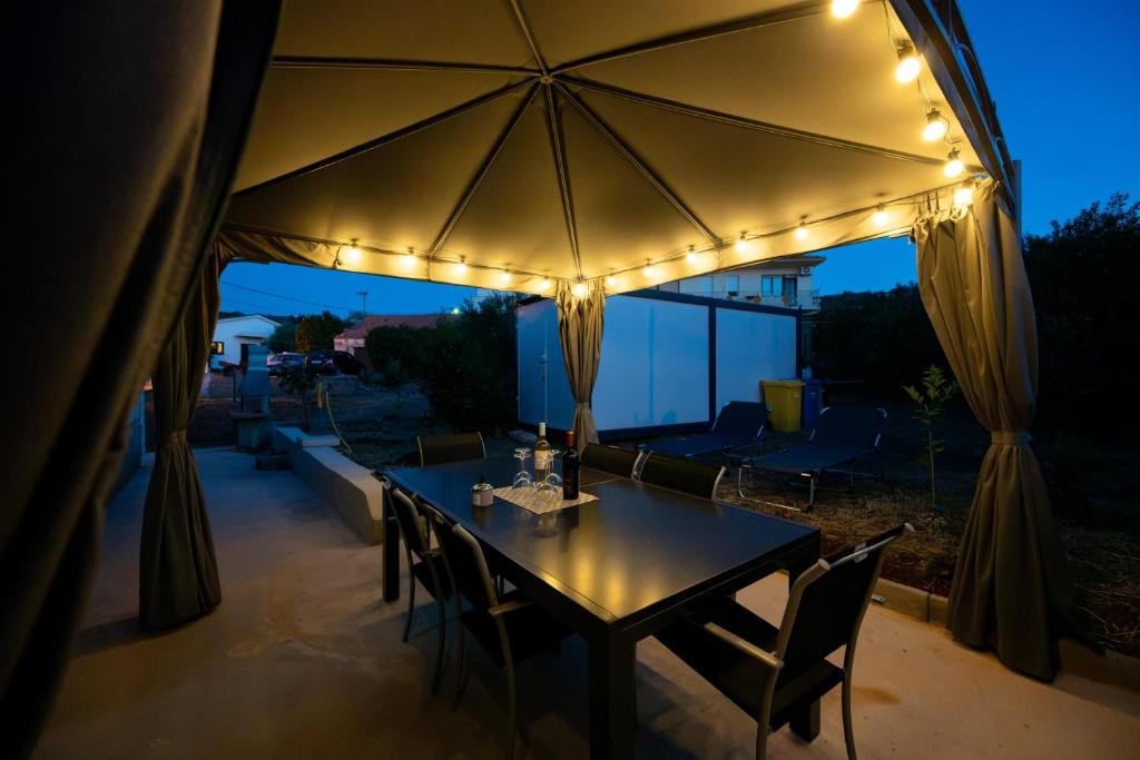 a table with chairs and an umbrella with lights at Kathy House in Slatine