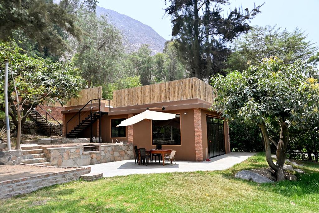 a house with a table and an umbrella at Chatowasi Mountain Lodge in Santa Eulalia