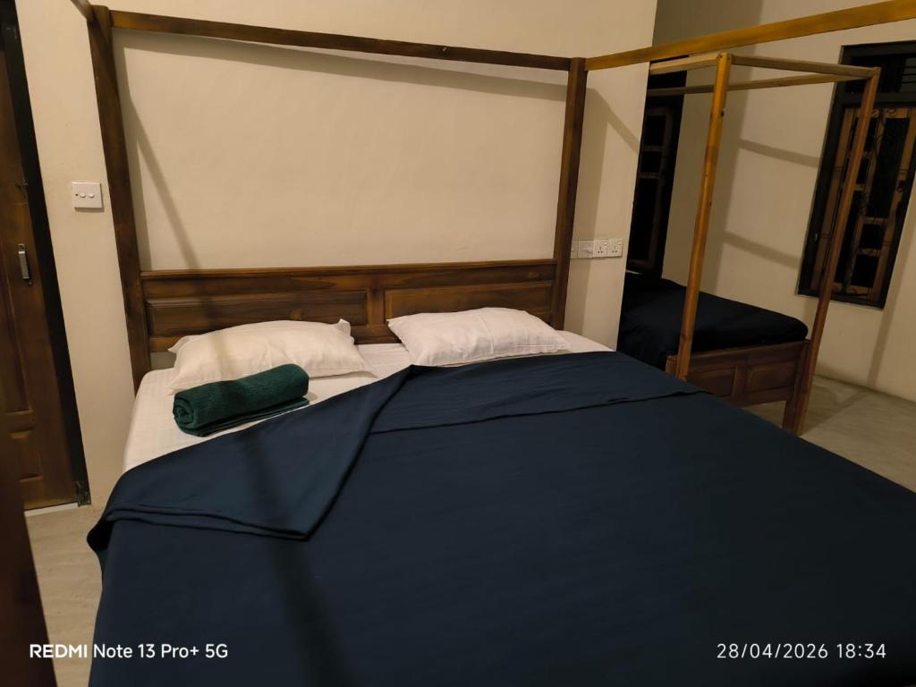 a bed with a blue comforter and two pillows at Hakkeem's Homestay in Arugam Bay