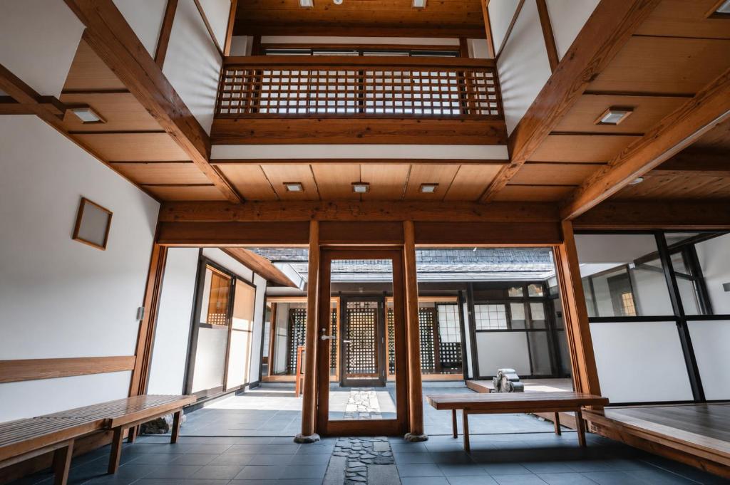 a large room with wooden ceilings and benches at ウエダハウス in Ueda