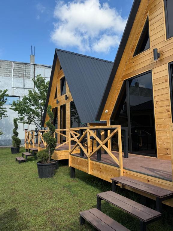 a wooden house with a black roof and benches at Cappadociagarden in Kutaisi