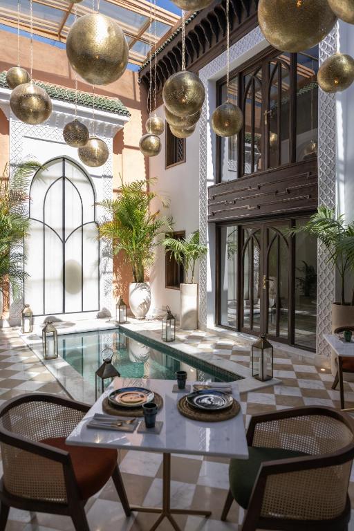 a dining room with a table and chairs and gold pendants at Riad Le Saadien ,Adult only in Marrakesh