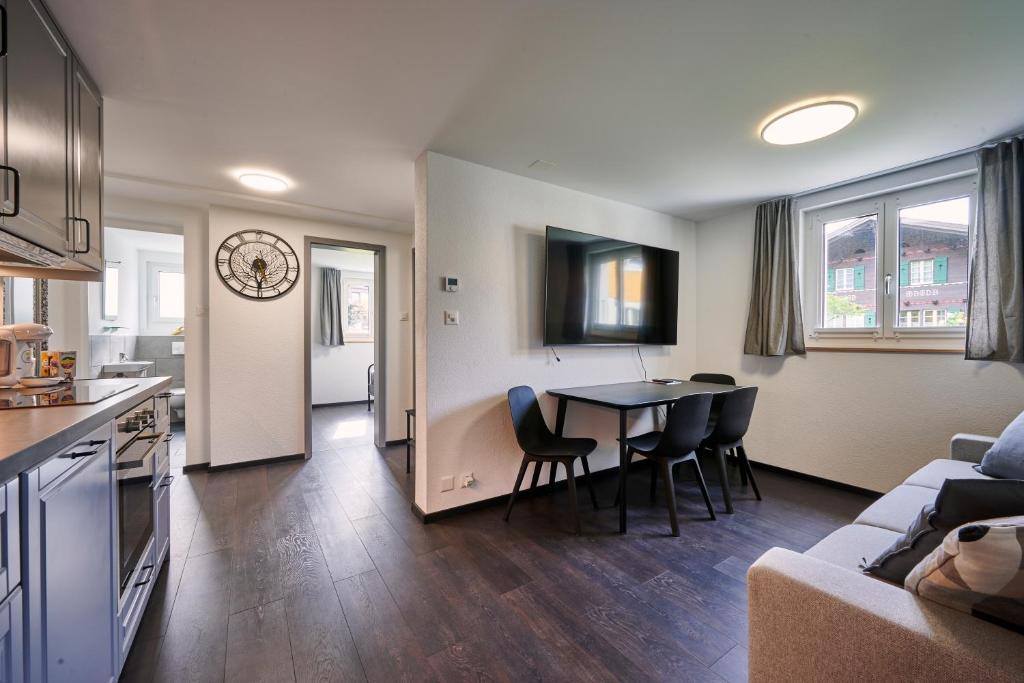 a kitchen and a living room with a table and chairs at Clarke's Lakeside Chalet 1 in Leissigen