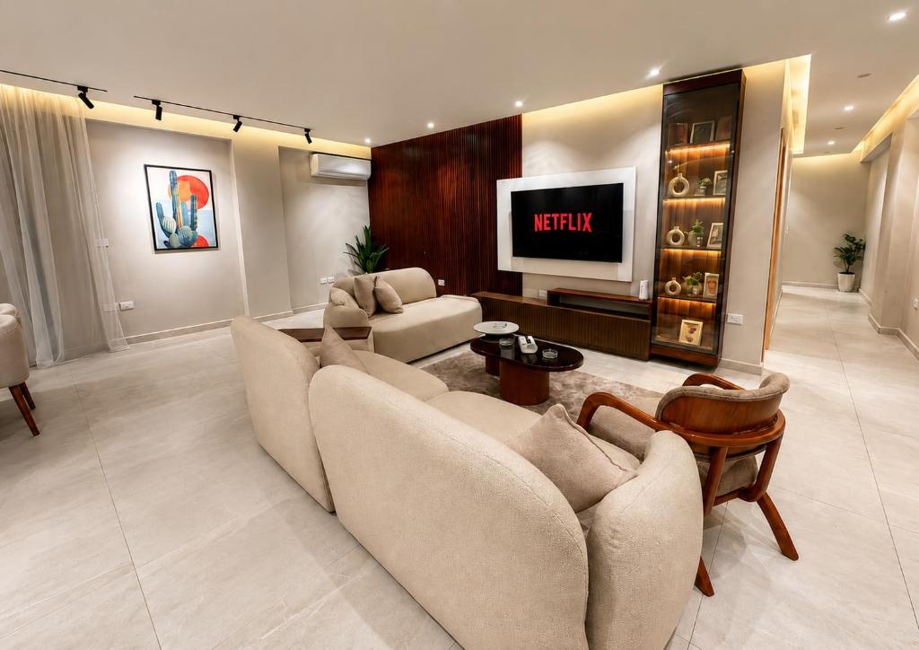a living room with a couch and a tv at Spacious 3BR Apartment in Prime Sheikh Zayed in Sheikh Zayed