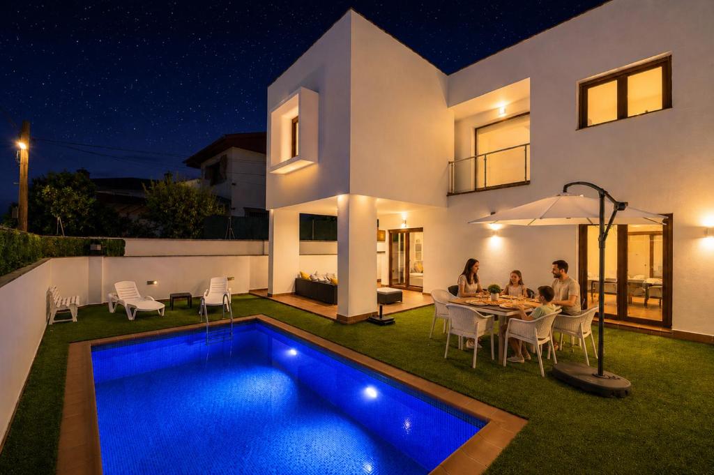 a group of people sitting around a table in front of a house at VILLA TAZA DE PLATA A in Huétor Vega