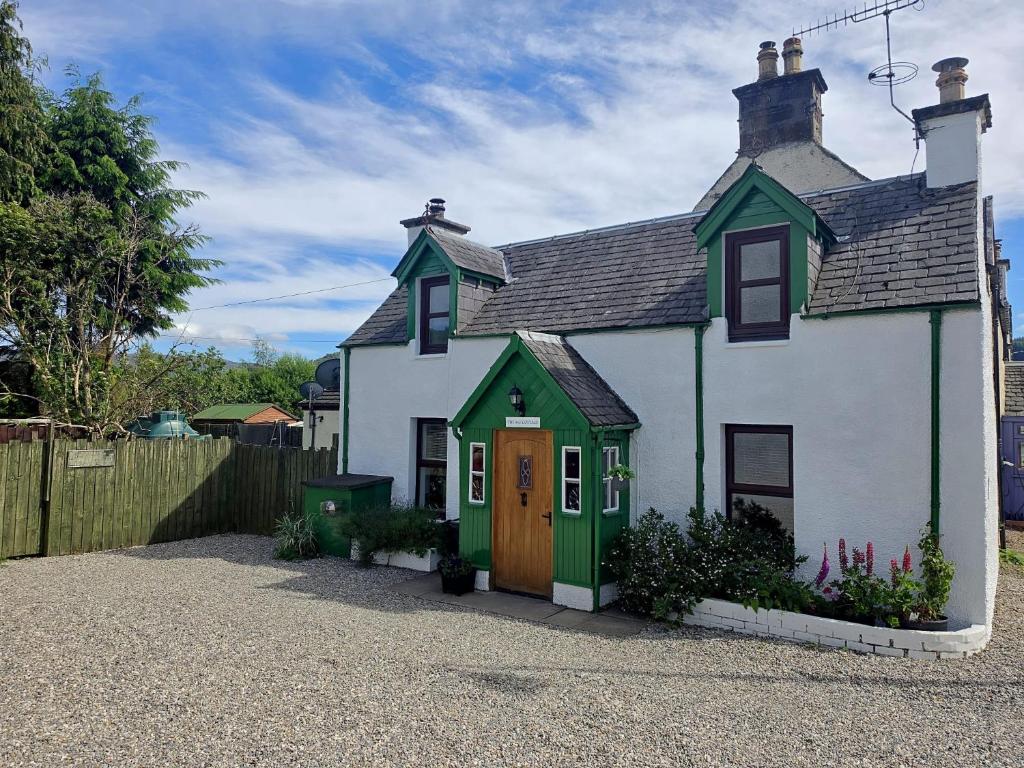 a small white and green house with a fence at Loch Ness village cottage for 2 with free parking & pets welcome in Drumnadrochit