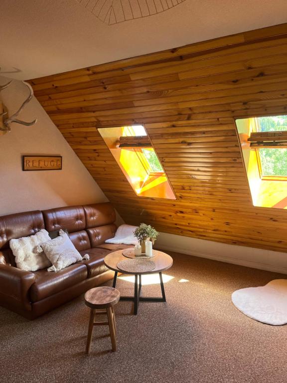 a living room with a leather couch and two windows at Riviera Lodge II in Allos