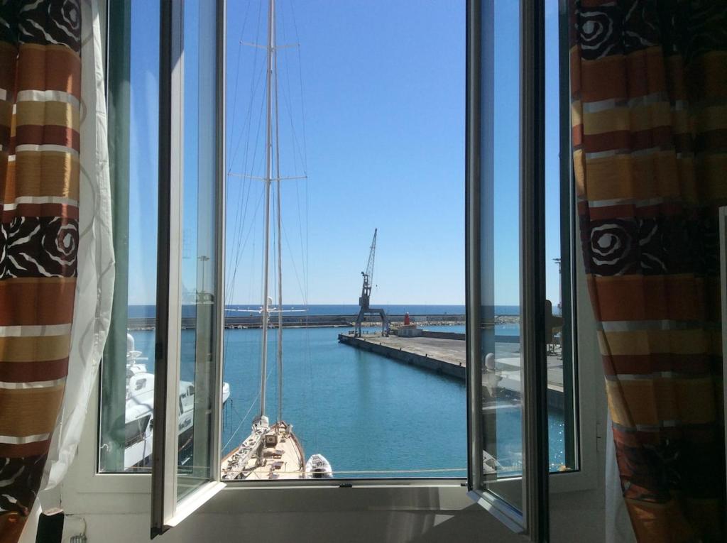 a window with a view of a boat in the water at Casetta sul Porto in Imperia