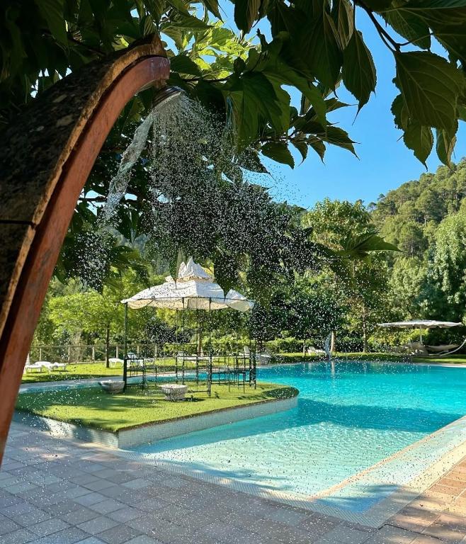 a swimming pool with an umbrella and a water fountain at Coto del Valle de Cazorla in Cazorla