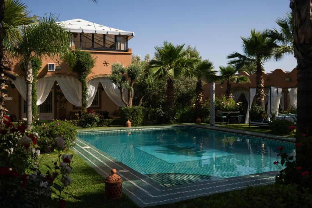 a swimming pool in front of a house with palm trees at Villa du Cedre in Marrakesh