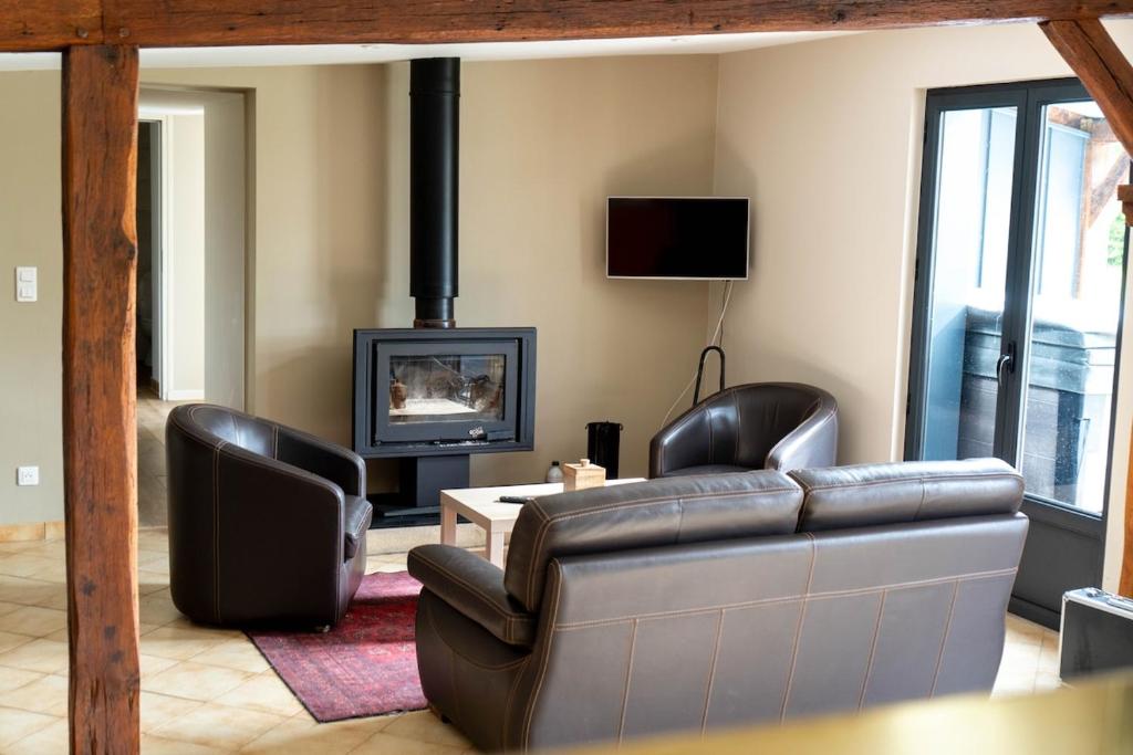 a living room with a leather couch and a fireplace at Le Rameau Gîte avec spa et étangs privés in Langey