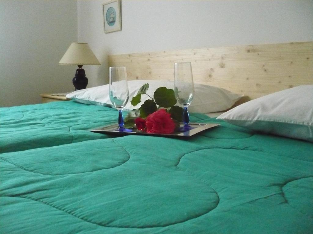 a green bed with two glasses and a tray with flowers at House Dina in Pula